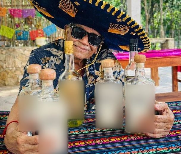 A guest in a big charro sombrero smiling behind the tasting bottles