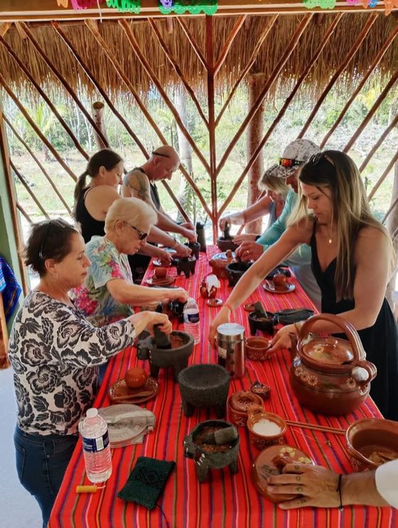 Guests at a red-cloth table, grinding and cooking