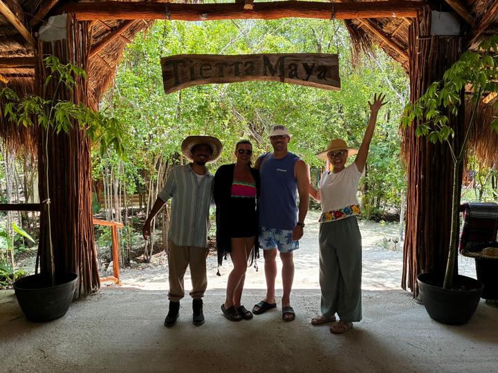 Four guests under the sign, one arm up
