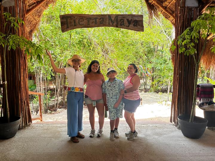 Four guests under the sign, one in a sombrero