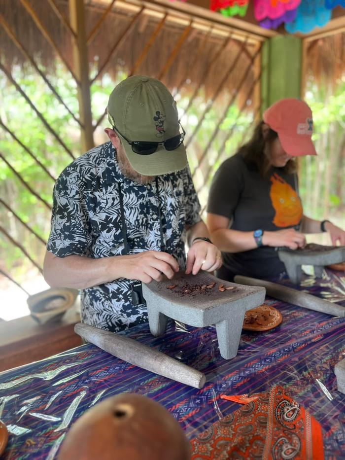 Two guests grinding cacao side by side