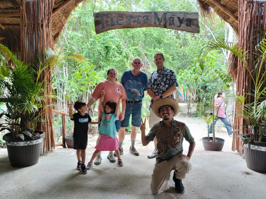 A family with two kids jumping, their guide kneeling