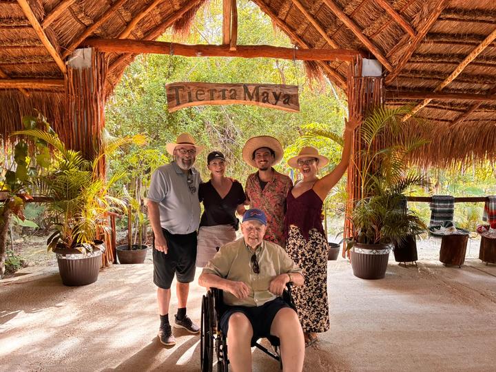 A family at the entrance, one guest in a wheelchair, with their guide